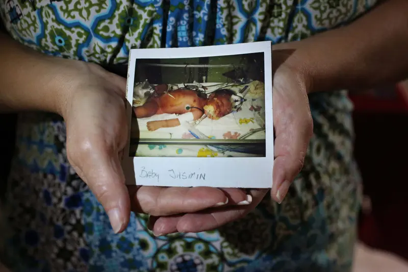 Hands holding a polaroid photo of a baby.