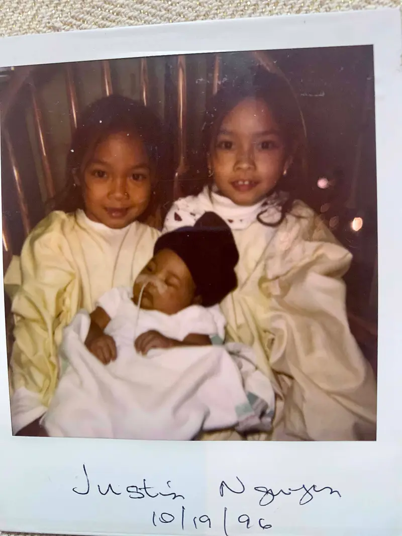 Two girls embrace their infant brother.