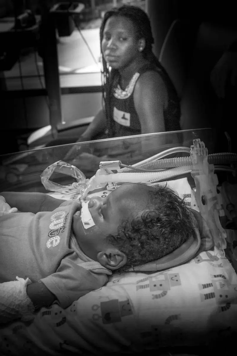 A woman looks at her son while he receives medical treatment.
