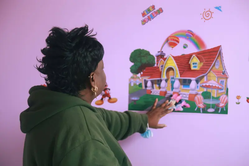 Jackie looking at a rainbow wall decoration of a cottage at one of her daycare centers.
