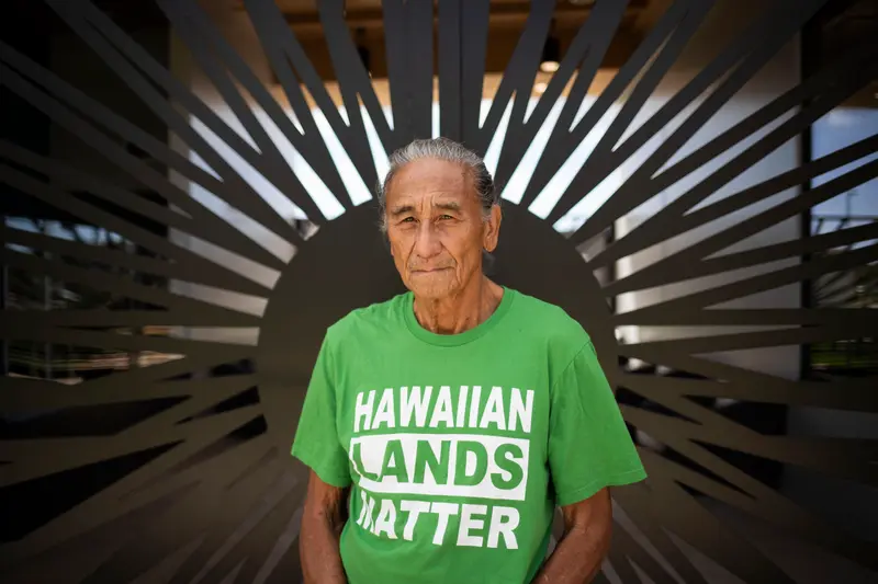Mike Kahikina wears a green shirt that says "Hawaiian Lands Matter."