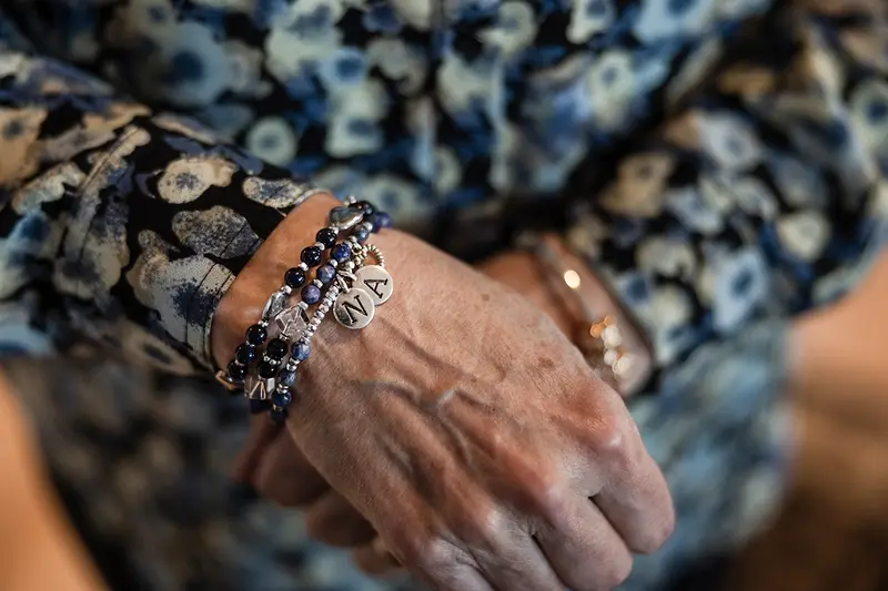 A bracelet of blue and black beads with two silver charms stamped with "N" and "A."