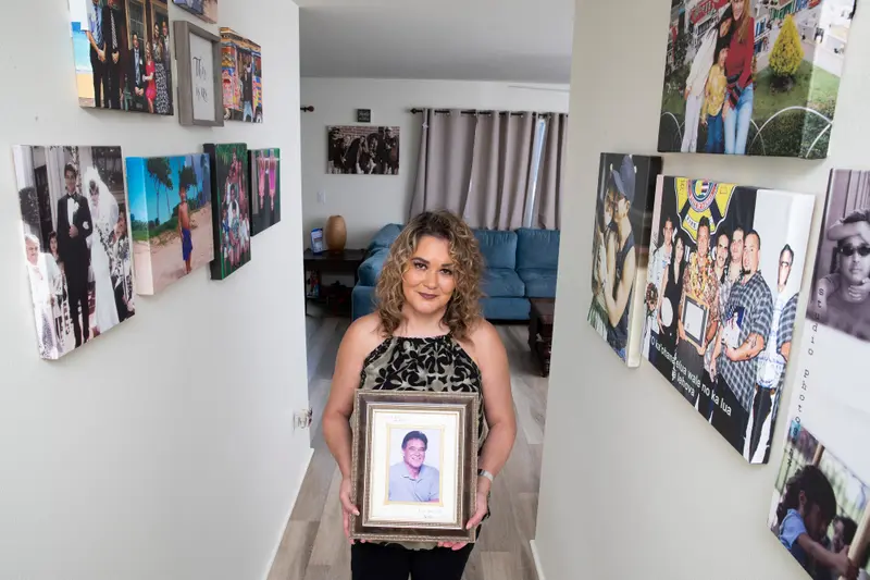 A woman stands in a hallway hung with family photos.