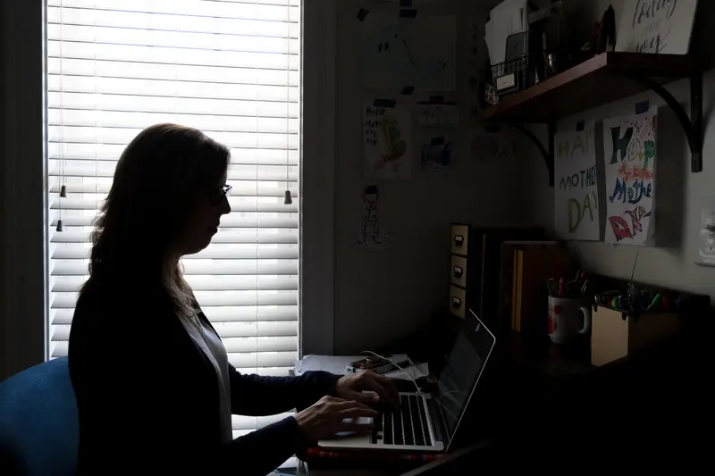 Donovan typing on a laptop, silhouetted by the light from a window behind her.