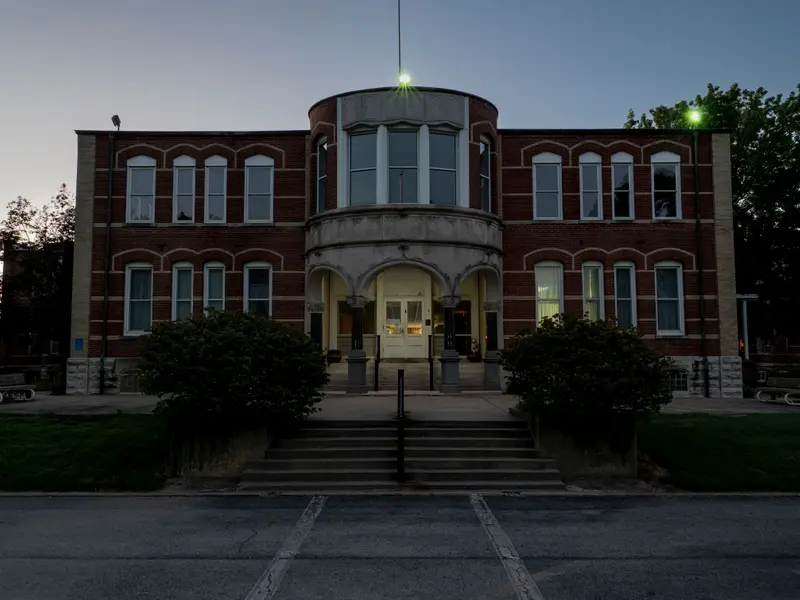 A two-story brick building with a round portico with white stone arches.