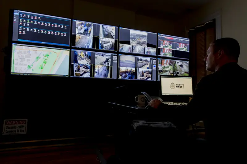 A man in a darkened room looks at a series of monitors.