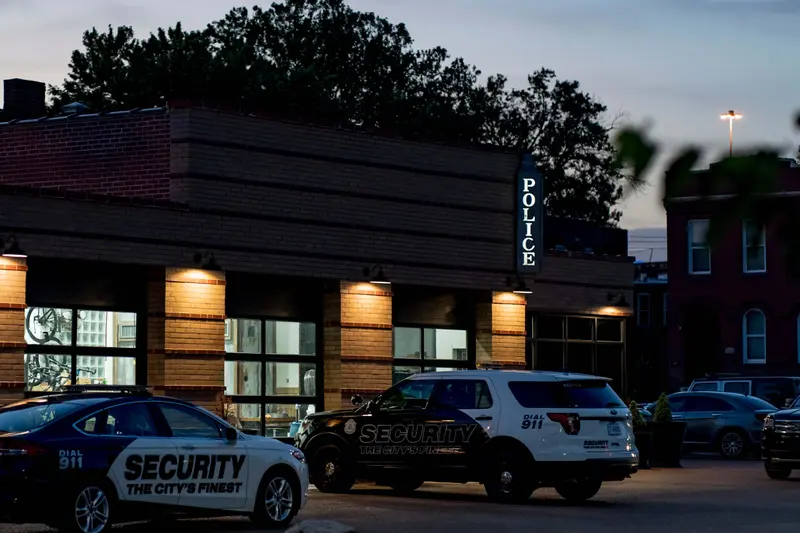 Cars marked "SECURITY" are parked outside an office with a lit sign reading "POLICE."