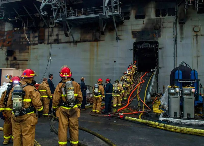 Firefighters enter a ship hatchway.