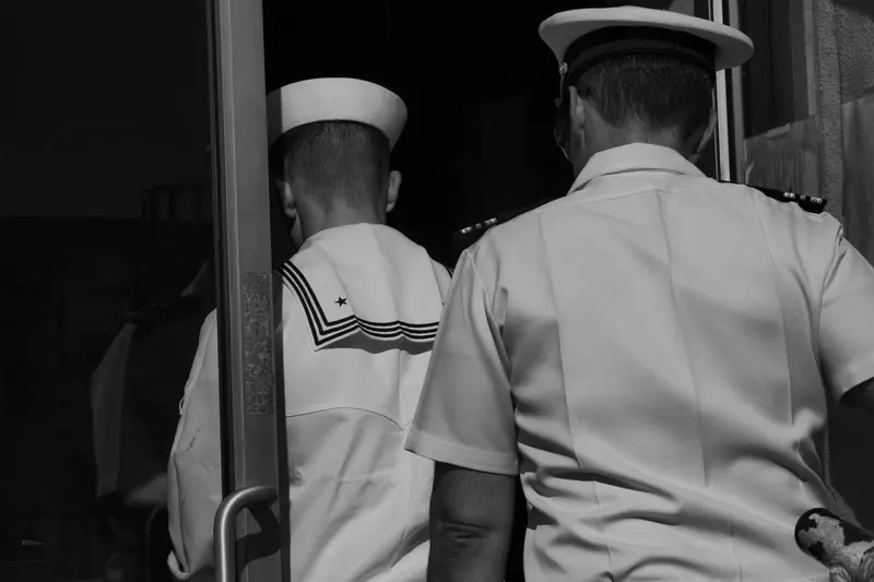 Two men in naval garb, seen from behind
