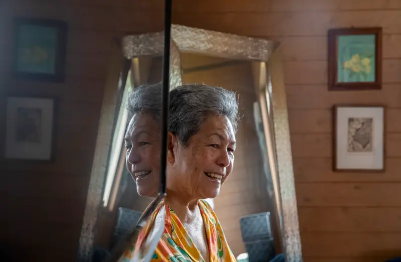 A woman smiles by a mirror in her home.