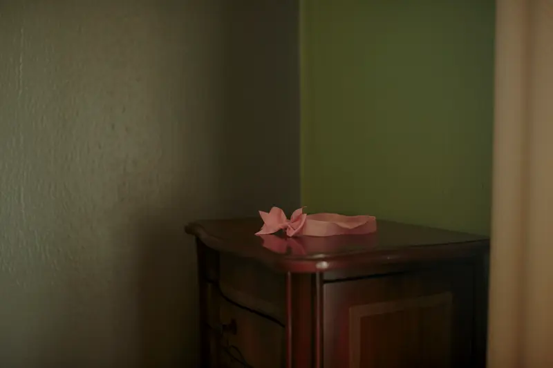 A pink headband with a bow sits on a table.