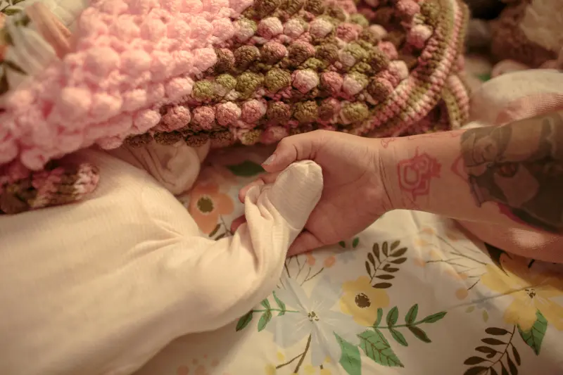 A hand holds a baby's foot.