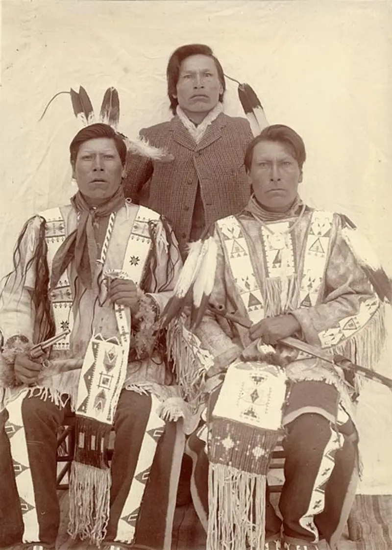 A black and white photo of three Native American men in 19th-century clothing.