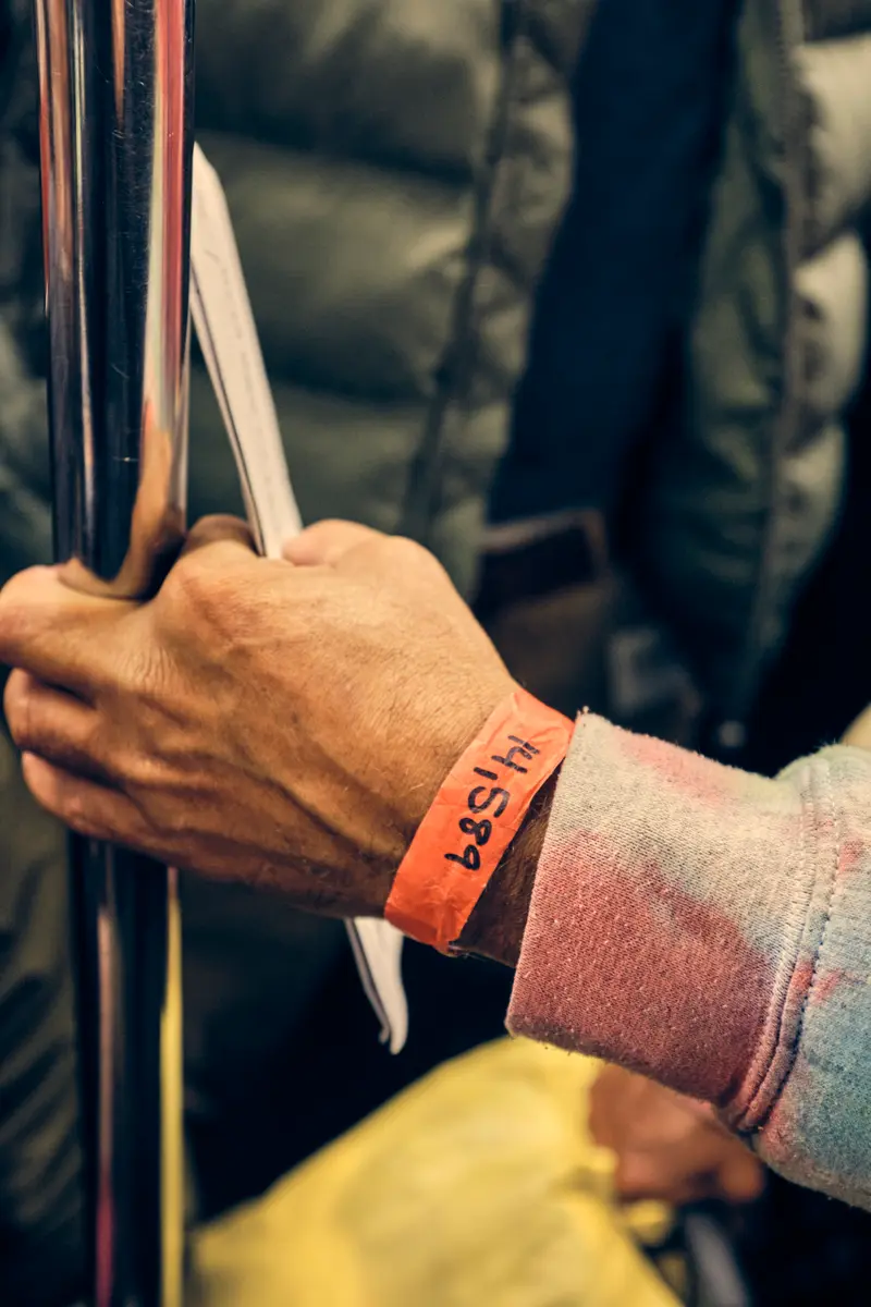 A close up of the orange wristband as Larez’s hand holds a subway pole.