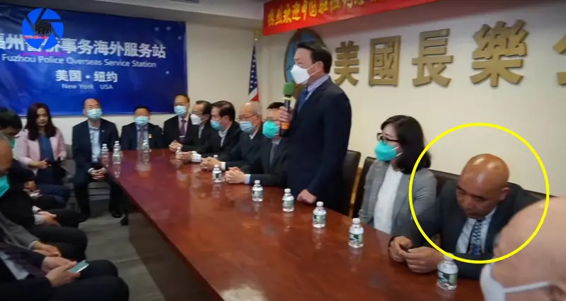 Asian people in business clothes gathered around a long table. Pan Muyong is in the lower right corner, possibly looking at a phone.