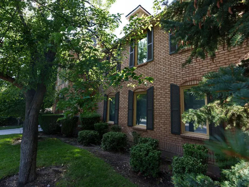 A two-story brick building surrounded by trees.