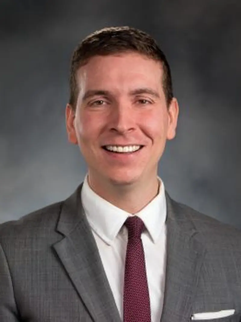 A professional headshot of a man in a suit