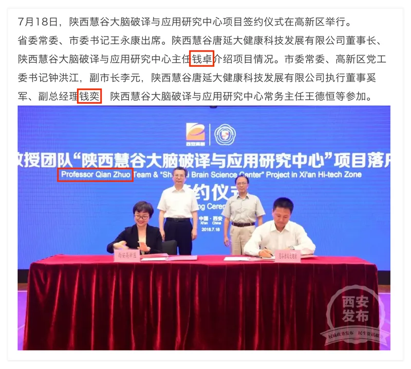 Tsien sits at a table with a woman, both have paperwork in front of them. Behind them is a screen with both Chinese and English text. The words "Professor Qian Zhuo" have been highlighted.
